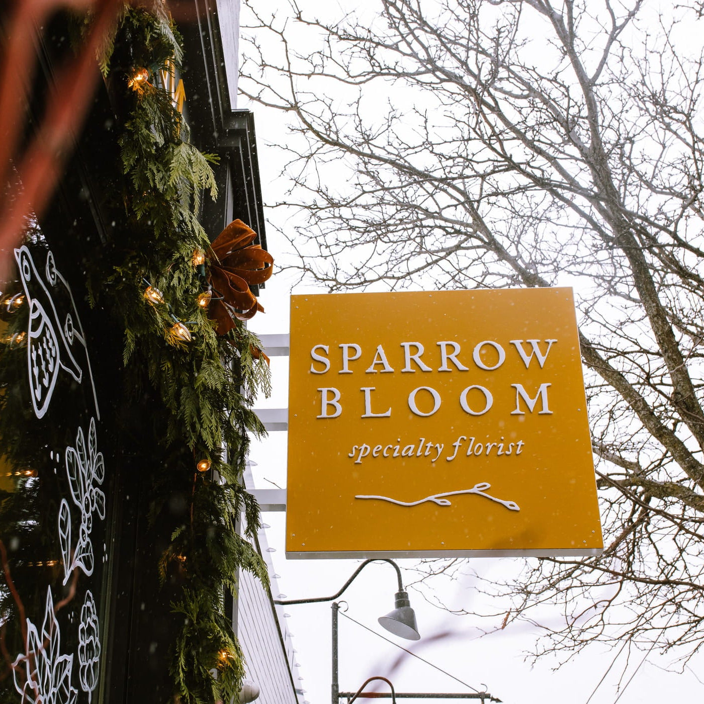 Sparrow Bloom specialty florist sign with decorative elements on a building exterior.