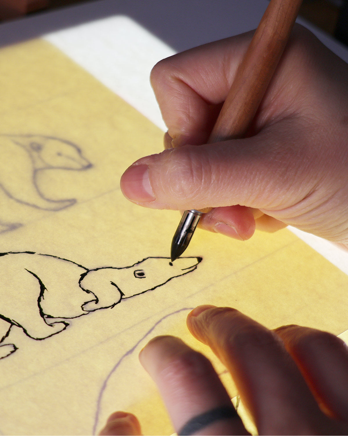 Hand drawing a dog on yellow paper with a pen