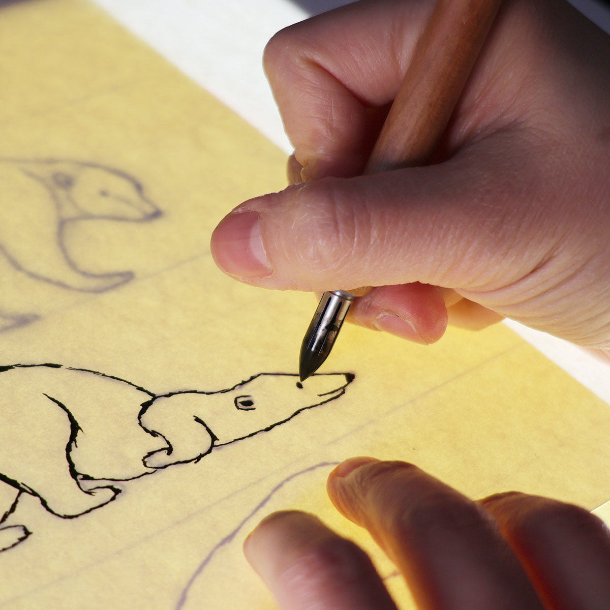 Hand drawing a dog on yellow paper with a pen