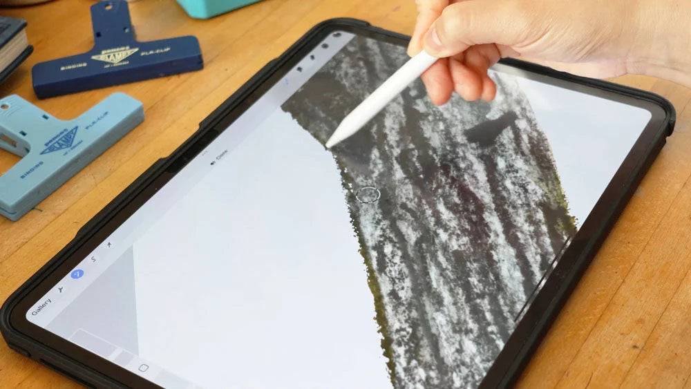 A person using a stylus on a tablet displaying a nature scene
