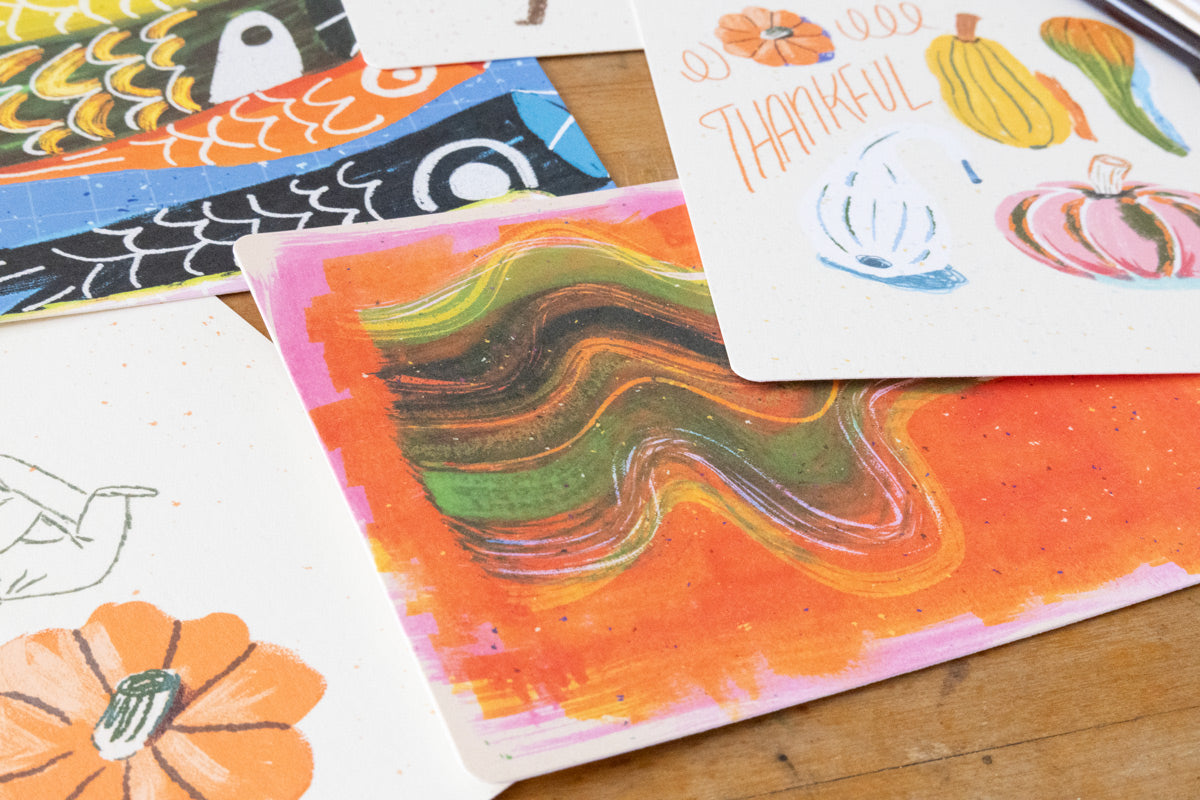 Close-up of illustrated postcards with an abstract koi design and a thankful card